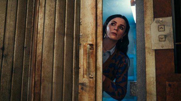 Aisling Bea as Sarah peering out of the lift