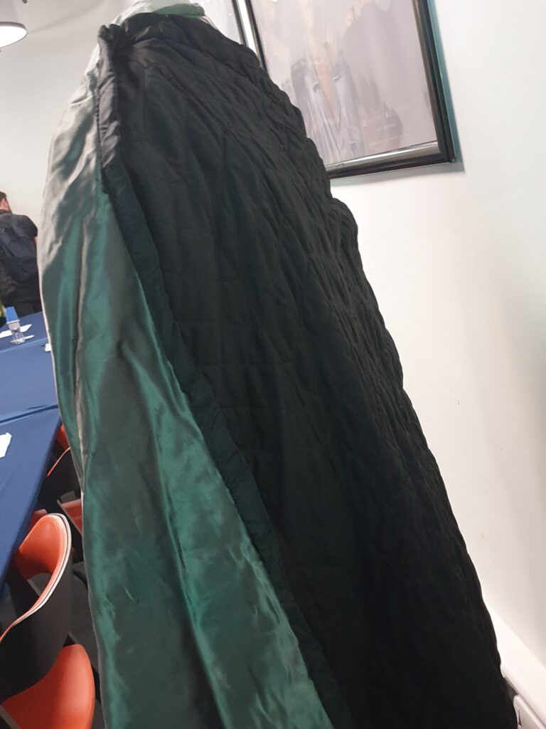 A side view of KIng Richard's green tunic and cloak on a mannequin