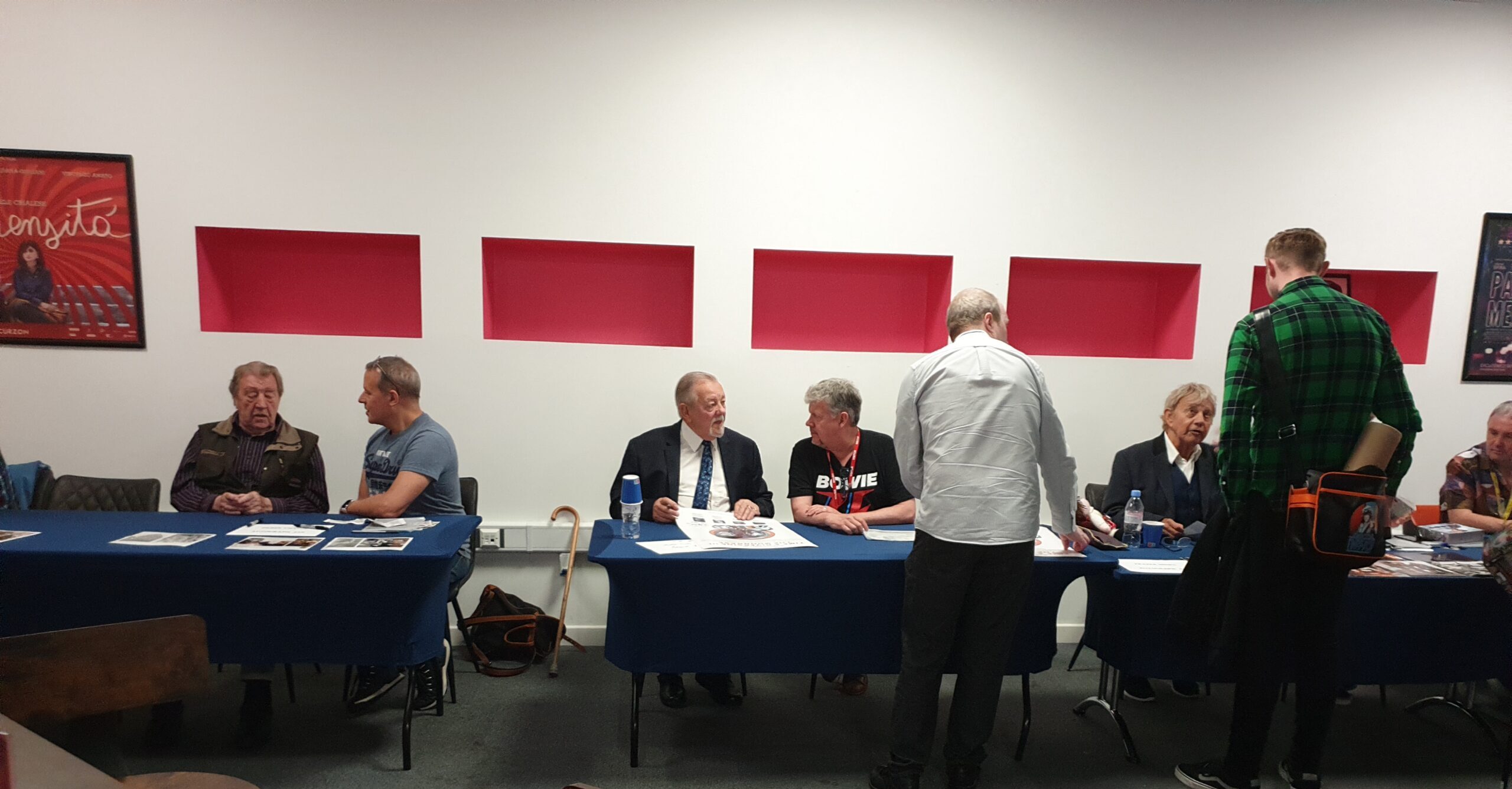 The guests sitting in the cinema foyer signing interviews