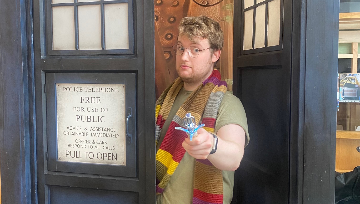 Harry, a man wearing glasses, a long scarf and holding a bright sonic screwdriver, stood in a big blue box.